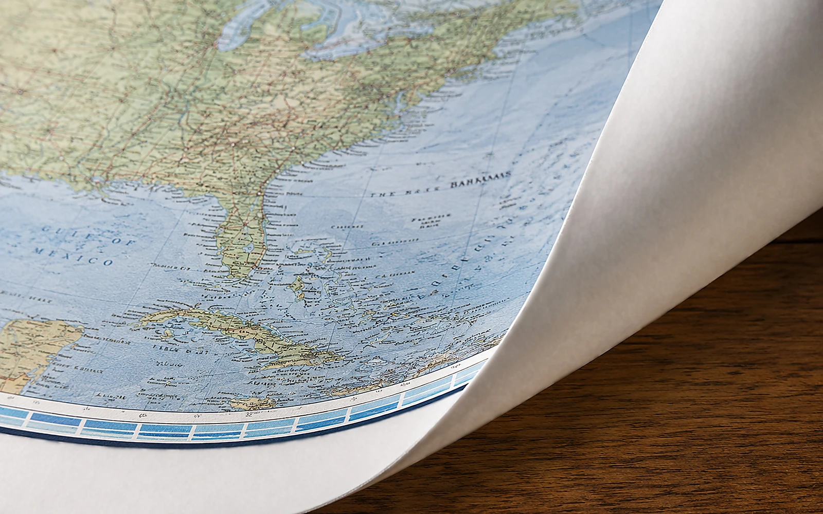 The corner of an unlaminated paper map curling back on a desk
