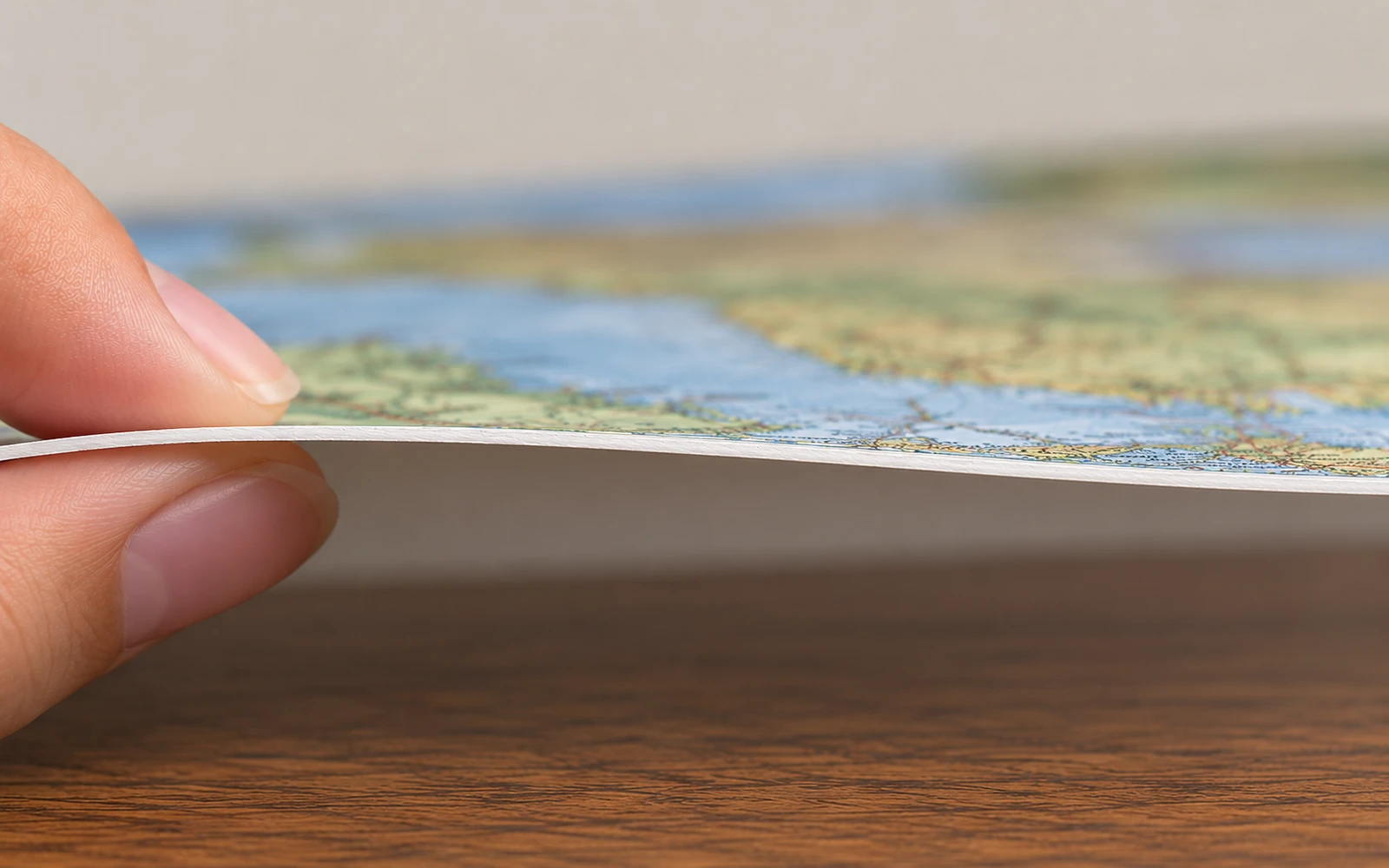 A hand lifting the corner of an unlaminated paper map