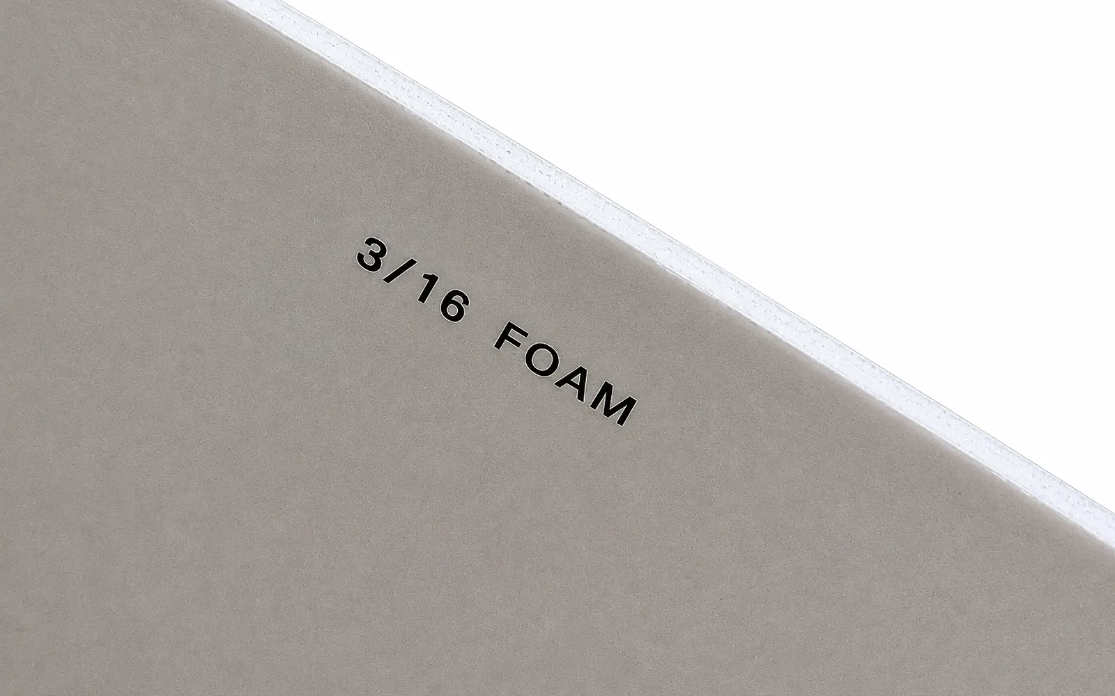The back of a grey board printed 3/16 foam, its thin white foam-core edge showing