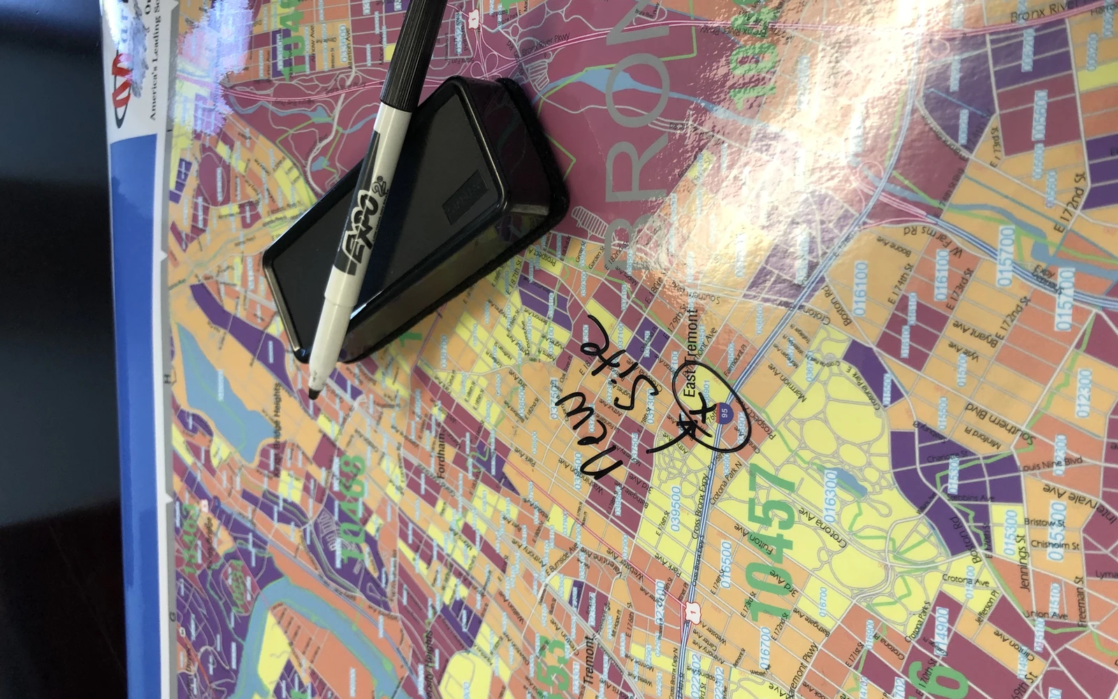 A dry-erase marker and eraser resting on a glossy laminated map written on by hand