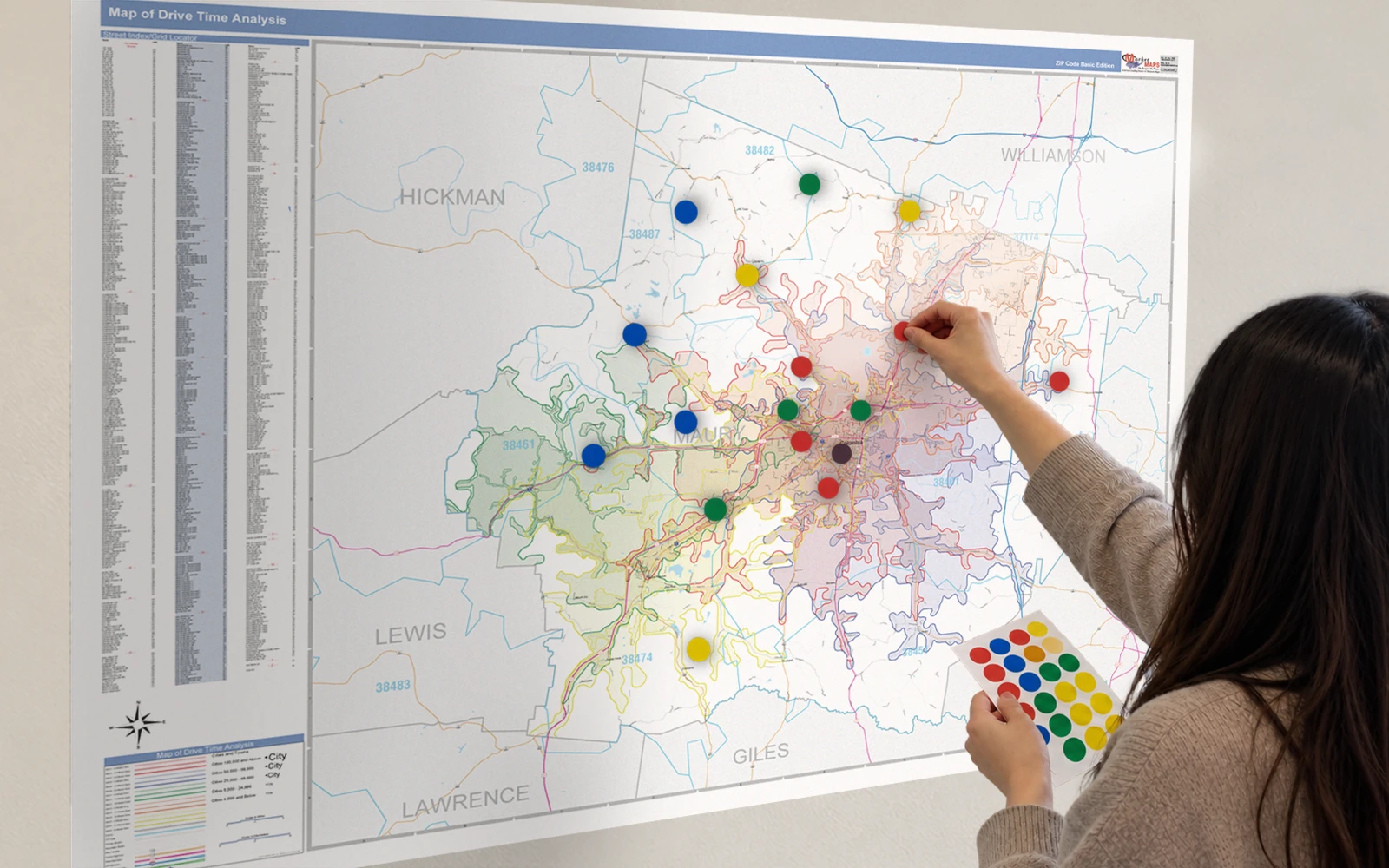 A woman placing coloured Mark-It Dots onto a laminated wall map