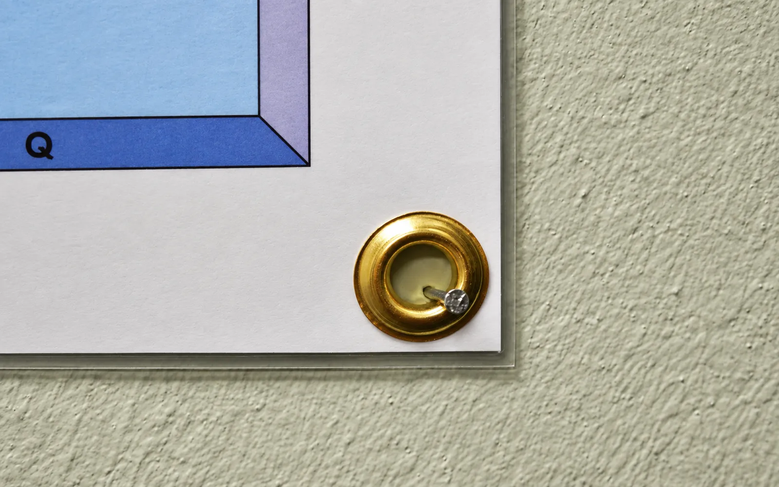 A brass grommet in the corner of a laminated map, hung on a nail