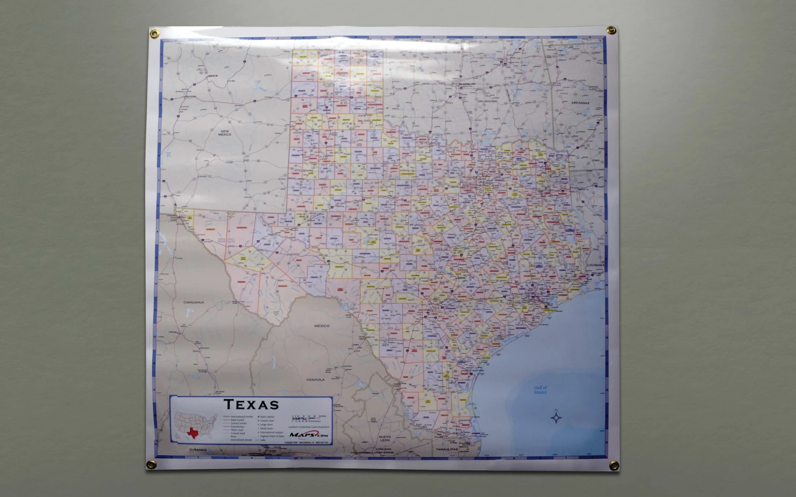 A Texas wall map hanging from grommets at its four corners
