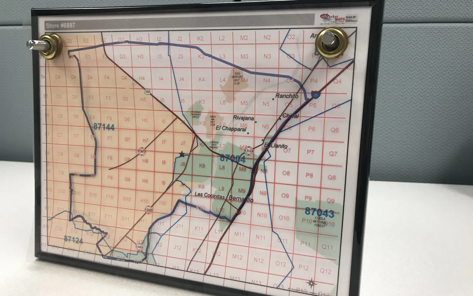 A framed map with a clear acetate overlay hanging from corner pegs