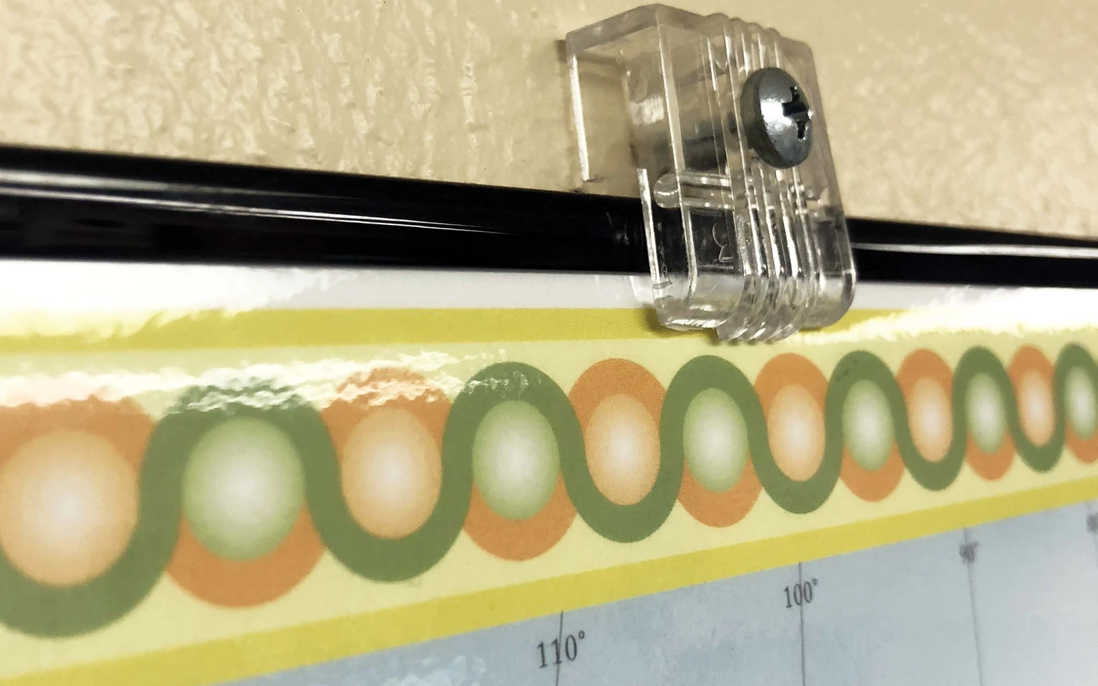 A clear mirror holder clipped over the top edge of a black frame