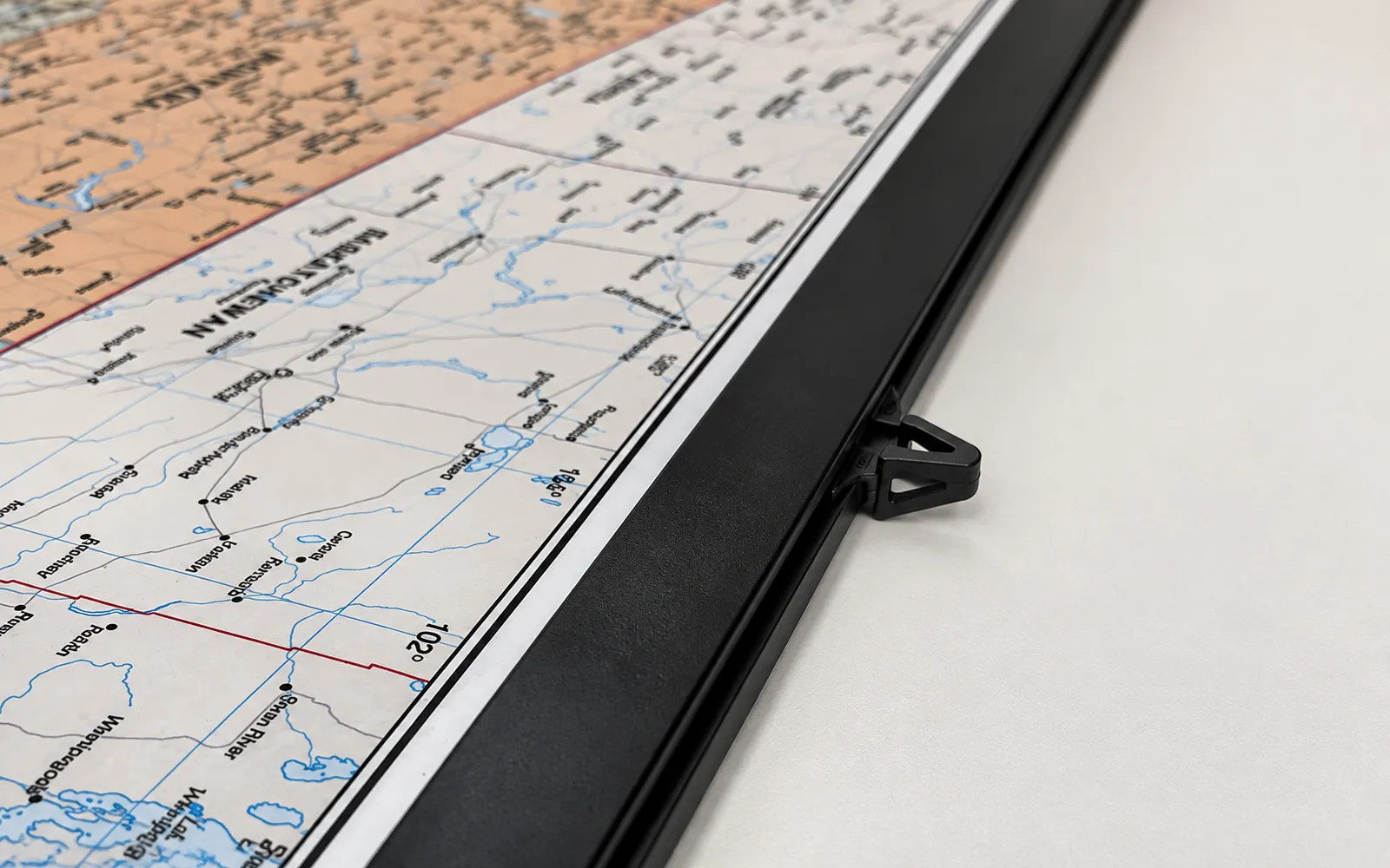 A black plastic rail running along the edge of a laminated map, seen at an angle