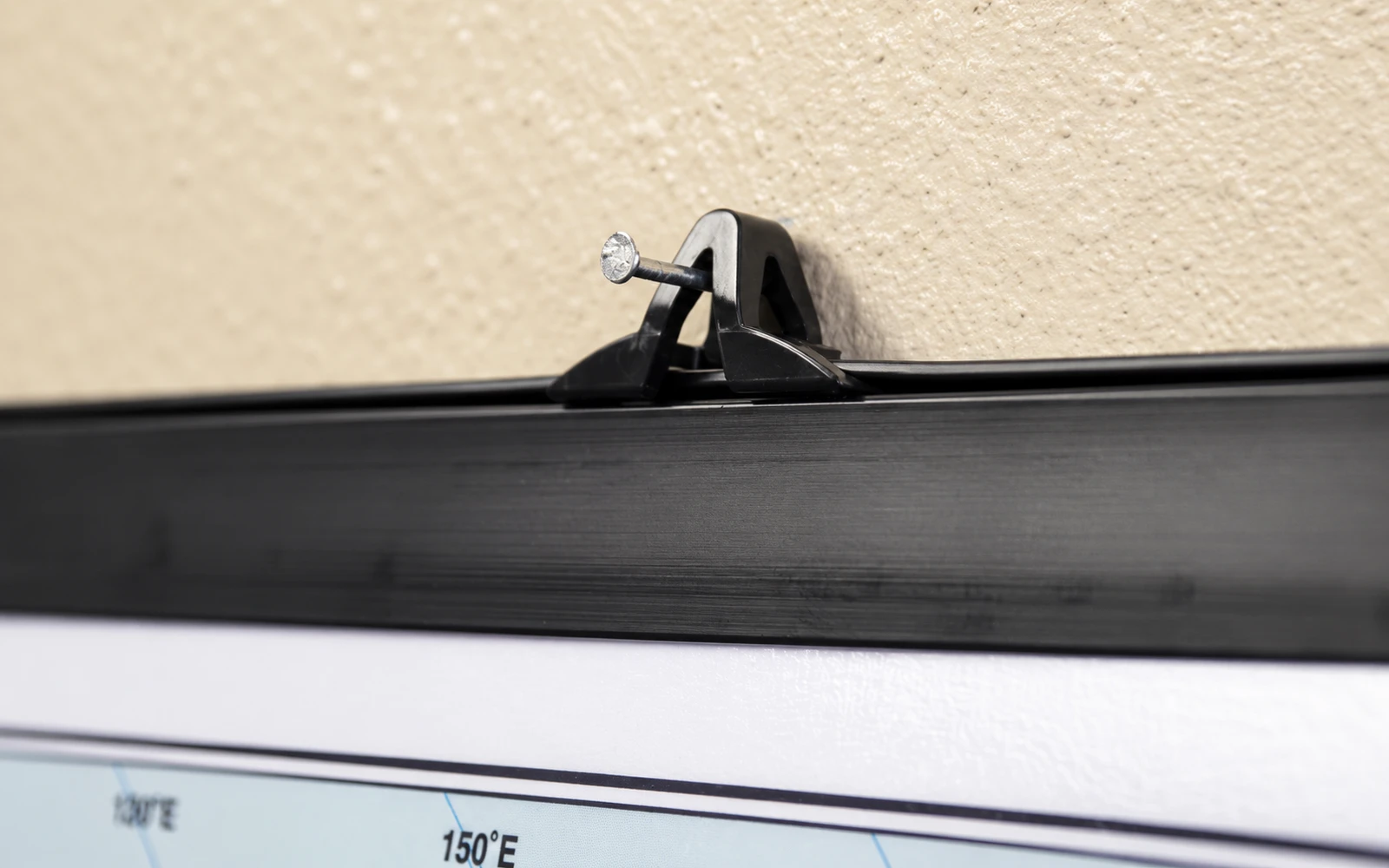 Close-up of a black plastic rail clipped along the edge of a wall map