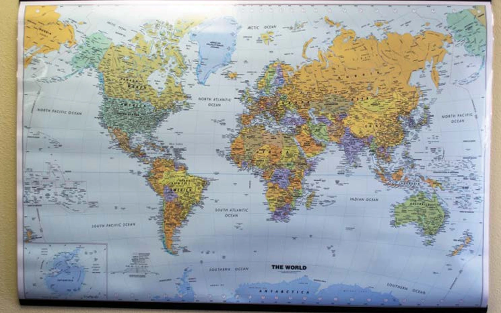 A world wall map hung on black plastic rails