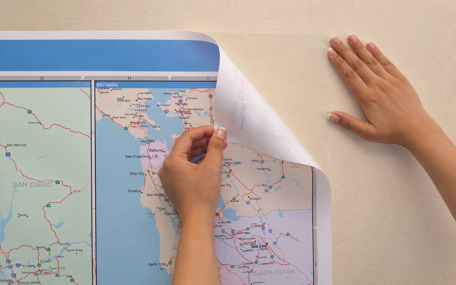 A ReSticker map being peeled back from a painted wall by hand