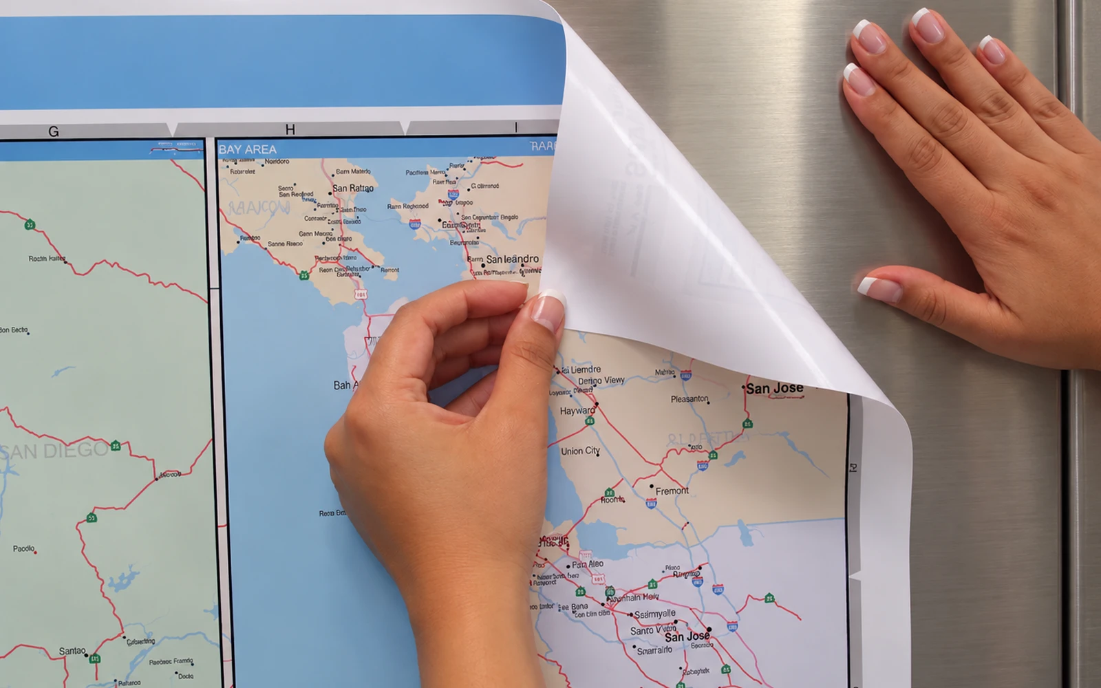 A ReSticker map being peeled back from a stainless steel surface