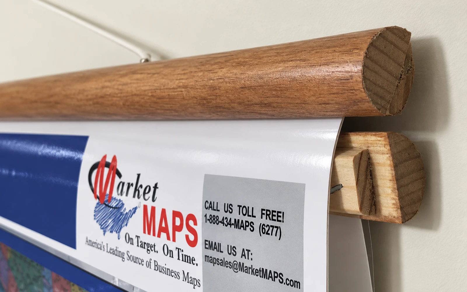 Close-up of a cherry-stained wooden rail fitted across the top of a wall map